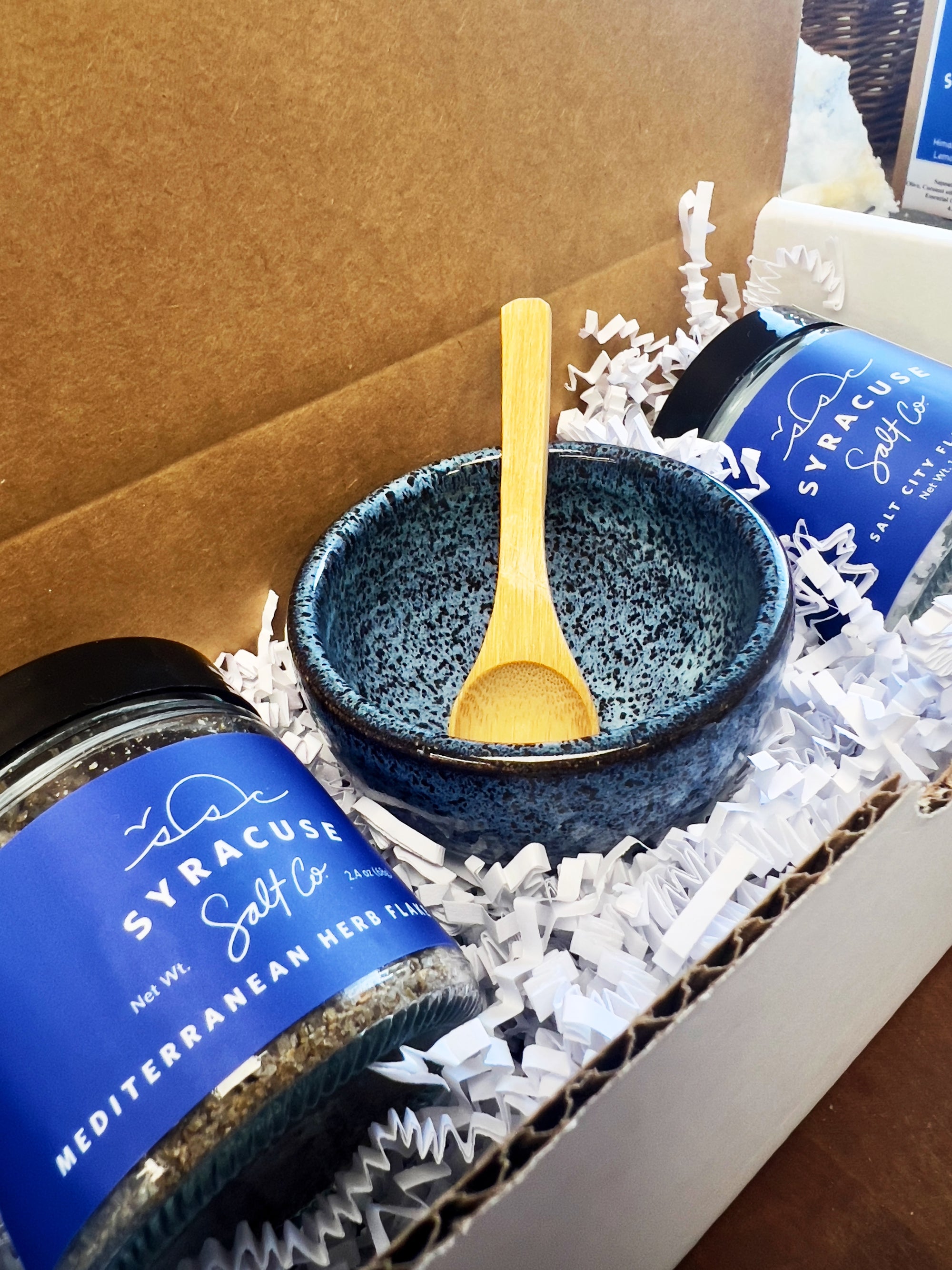 Salt pouring into a blue speckled bowl beside a Syracuse Salt Co. jar